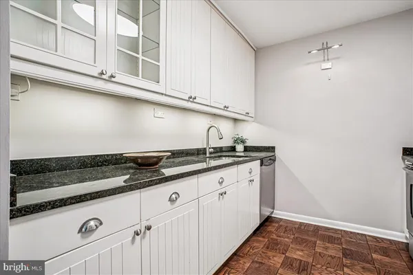 a kitchen with granite countertop white cabinets and sink