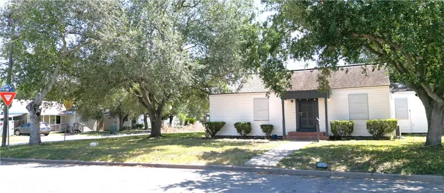 a view of a house with a yard and large tree