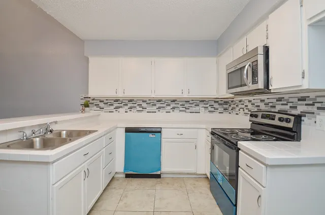 a kitchen with granite countertop a sink stove and cabinets