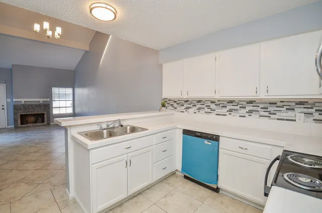 a kitchen with white cabinets sink and stove