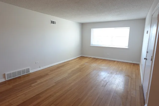 an empty room with wooden floor and bathroom view