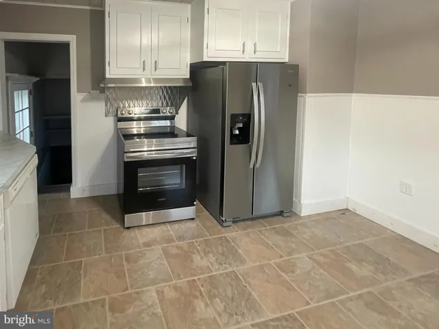 a kitchen with granite countertop a refrigerator and a stove top oven