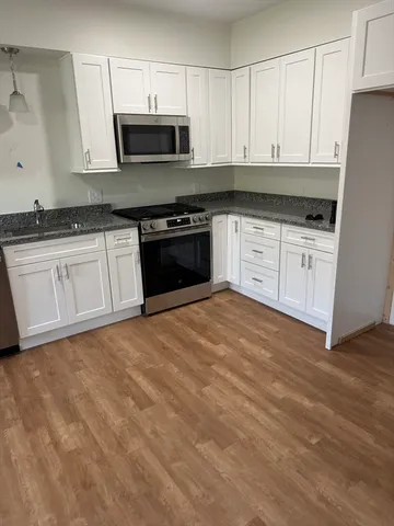 a kitchen with granite countertop white cabinets and stainless steel appliances