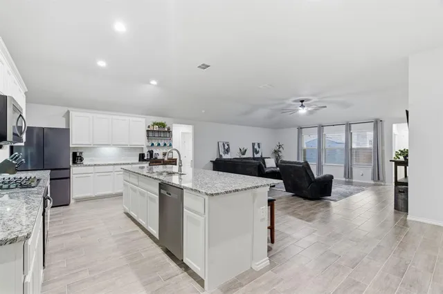 a large white kitchen with a stove a sink dishwasher and a fireplace with wooden floor