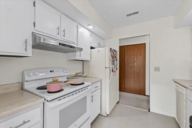 a kitchen with white cabinets and refrigerator