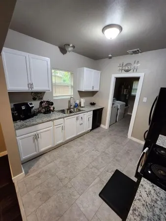a kitchen with granite countertop a stove sink and cabinets
