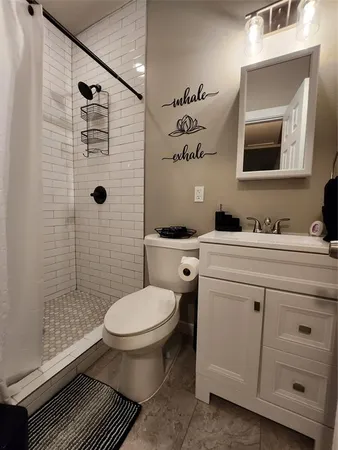 a bathroom with a granite countertop toilet sink and mirror
