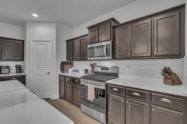 a kitchen with stainless steel appliances granite countertop a stove a sink and a microwave