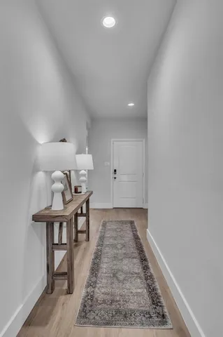 a view of a hallway to room with wooden floor