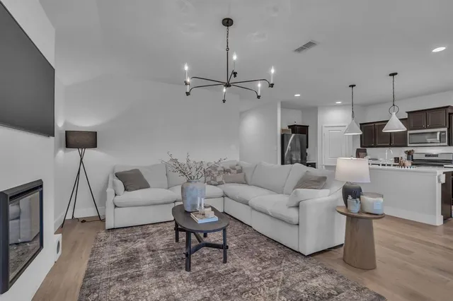 a living room with furniture kitchen view and a chandelier