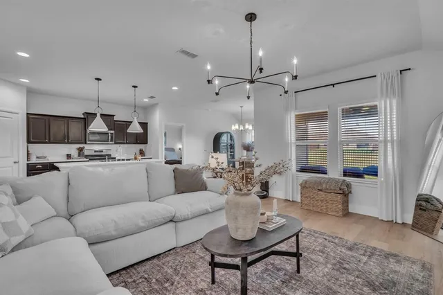 a living room with furniture kitchen view and a chandelier