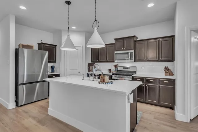 a kitchen with kitchen island a sink stainless steel appliances and cabinets