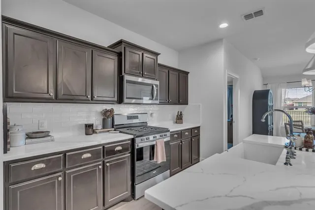 a kitchen with stainless steel appliances granite countertop a sink stove and microwave