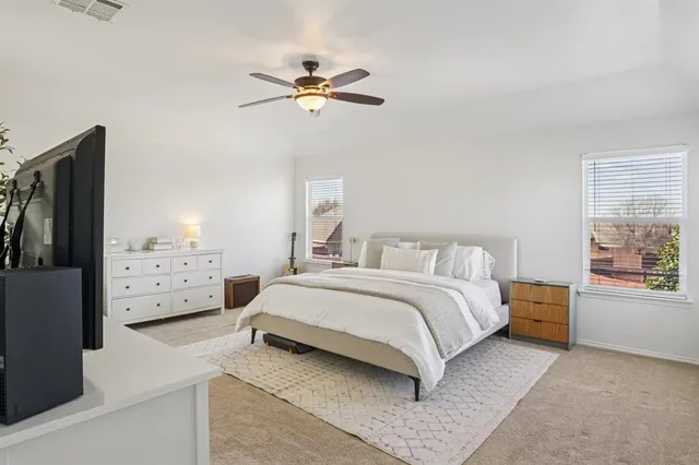 a bedroom with a bed a dresser and flat screen tv