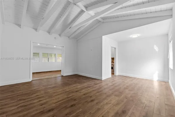 a view of an empty room with window and wooden floor