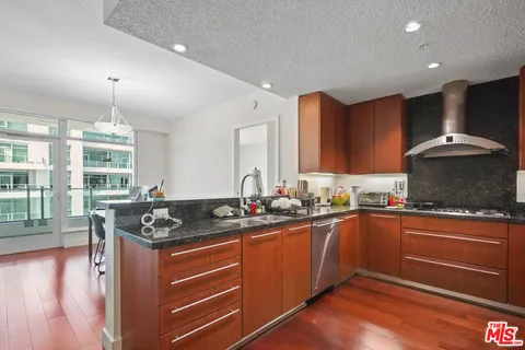 a kitchen with granite countertop stainless steel appliances a sink and wooden floor