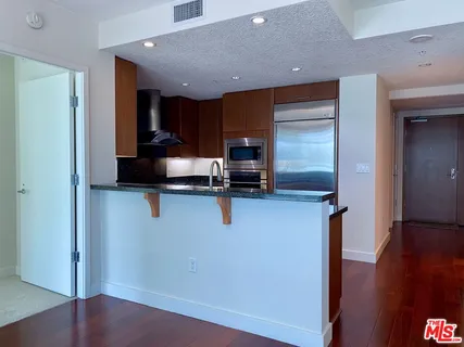 a kitchen with granite countertop a sink dishwasher a stove and black cabinets with wooden floor