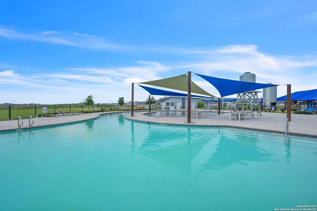 a view of swimming pool with lawn chairs and iron fence