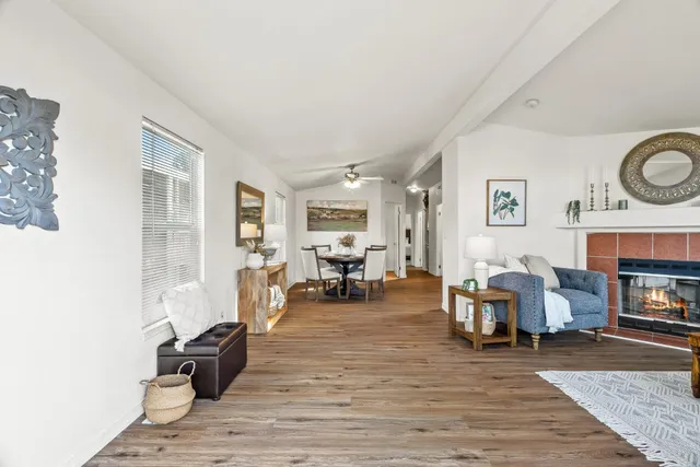 a living room with fireplace furniture and a dining table with wooden floor