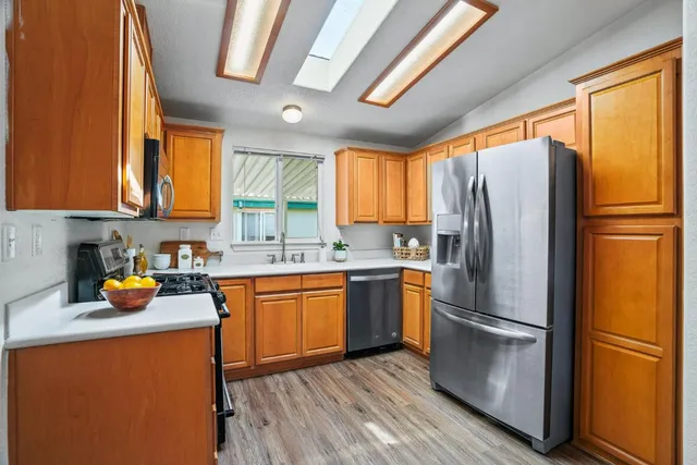 a kitchen with stainless steel appliances a refrigerator a sink a center island cabinets and wooden floor