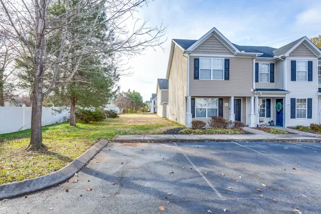 a view of a big yard in front of a brick house with large windows