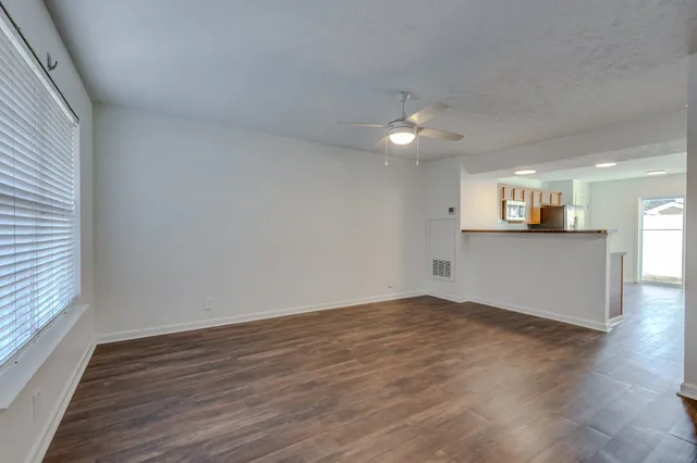 an empty room with wooden floor and windows