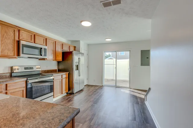 a kitchen with stainless steel appliances granite countertop a stove top oven a sink dishwasher and a refrigerator with wooden floor