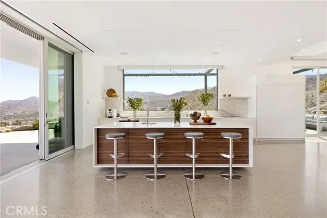 a living room with couches a coffee table and with potted plants with wooden floor