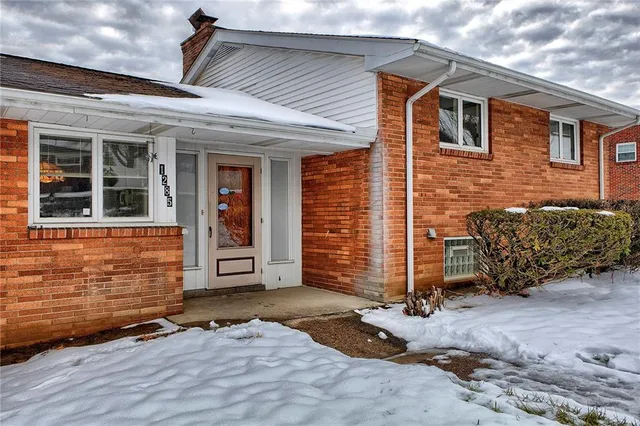 a front view of a house with a yard covered with snow