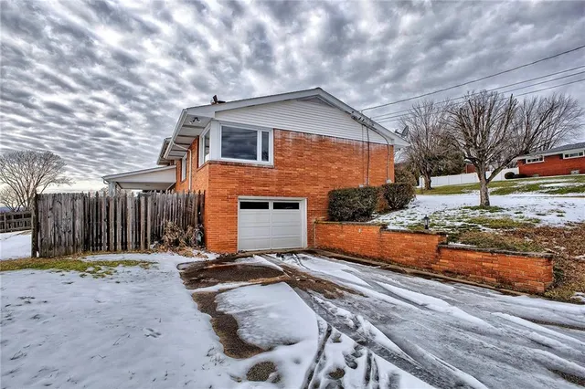 a front view of a house with a yard covered with snow