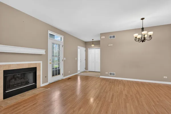 a view of an empty room with wooden floor fireplace and a window