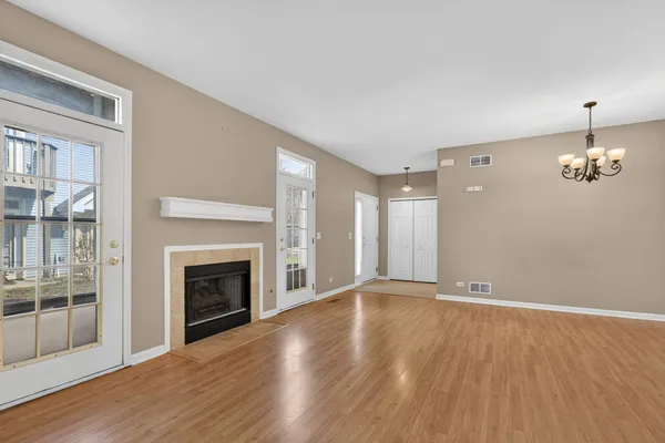 an empty room with wooden floor fireplace and windows