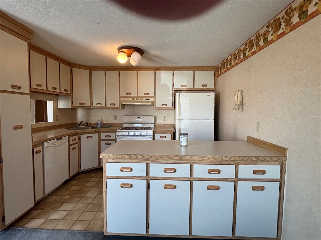 241 Broadway Road, Unit 53 Dracut, MA 01826 - Photo 5 of 24 a kitchen with kitchen island granite countertop cabinets and refrigerator