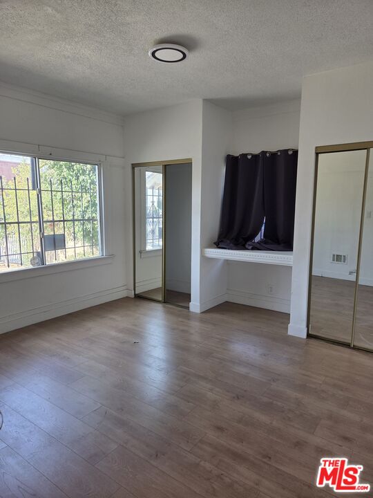1612 Arlington Avenue Los Angeles, CA 90019 - Photo 7 of 24 an empty room with wooden floor and windows