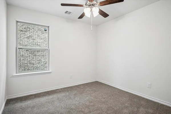 an empty room with a window and a fan