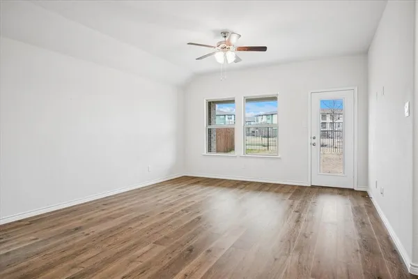 a view of an empty room with a window and wooden floor