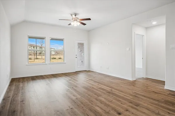a view of an empty room with wooden floor and a window