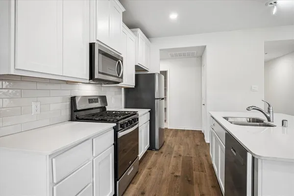 a kitchen with stainless steel appliances granite countertop a sink stove and refrigerator