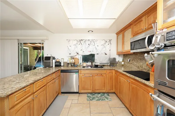 a large kitchen with stainless steel appliances granite countertop a sink and dishwasher a stove top oven with wooden floor