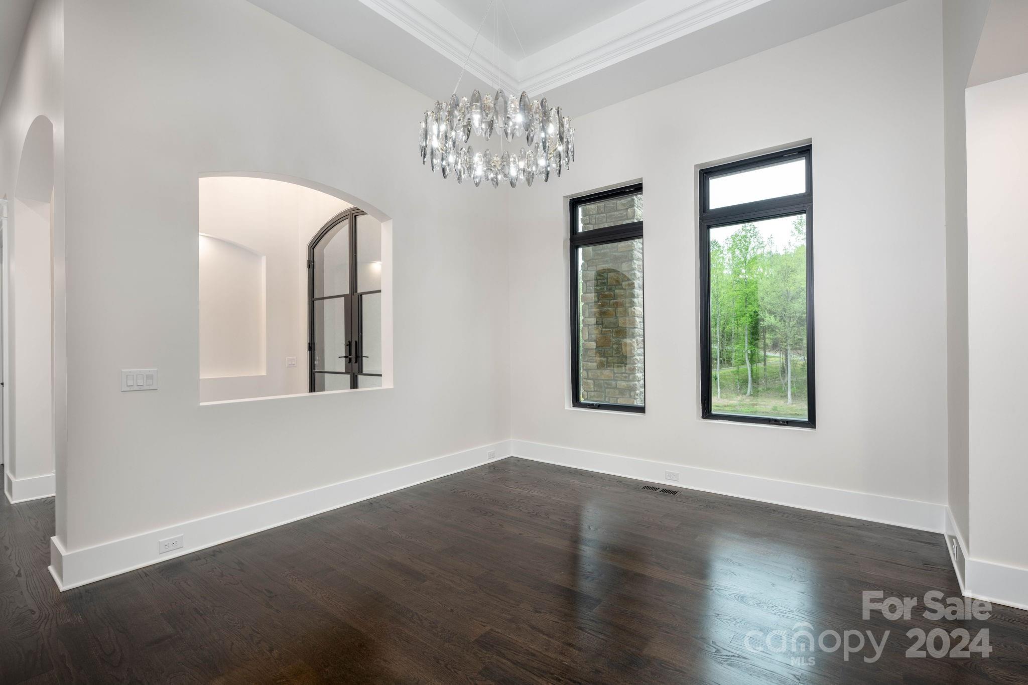 10290 Enclave Circle Concord, NC 28027 - Photo 28 of 48 an empty room with wooden floor chandelier and windows