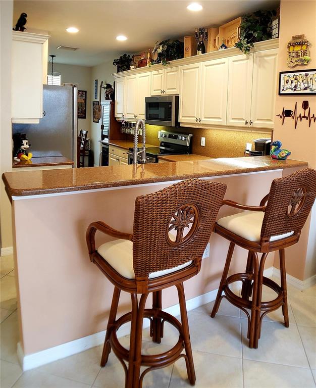 5662 Whitehead Street Bradenton, FL 34203 - Photo 17 of 51 a kitchen with a table chairs refrigerator and microwave