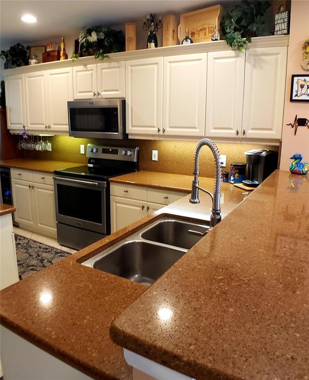 5662 Whitehead Street Bradenton, FL 34203 - Photo 20 of 51 a kitchen with stainless steel appliances a stove a sink a microwave a refrigerator and cabinets