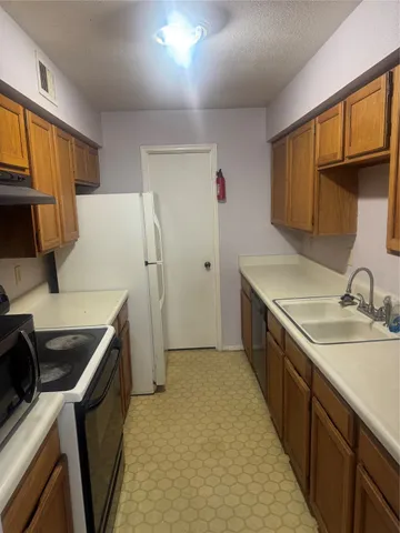 a kitchen a sink a refrigerator and cabinets