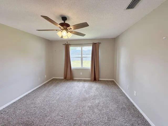 an empty room with windows and fan