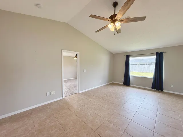 a view of an empty room with a ceiling fan and a window