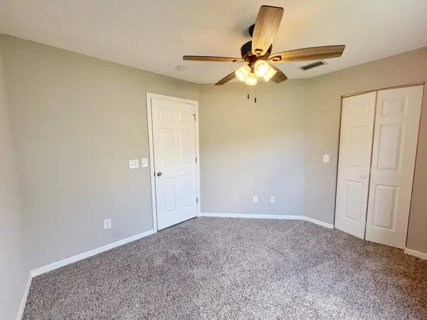 a view of an empty room with a ceiling fan and a window