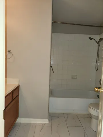 a bathroom with a granite countertop bathtub shower sink vanity and toilet