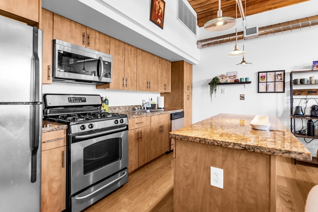 130 John Street, Unit 216 Lowell, MA 01852 - Photo 5 of 17 a kitchen with a stove and a microwave