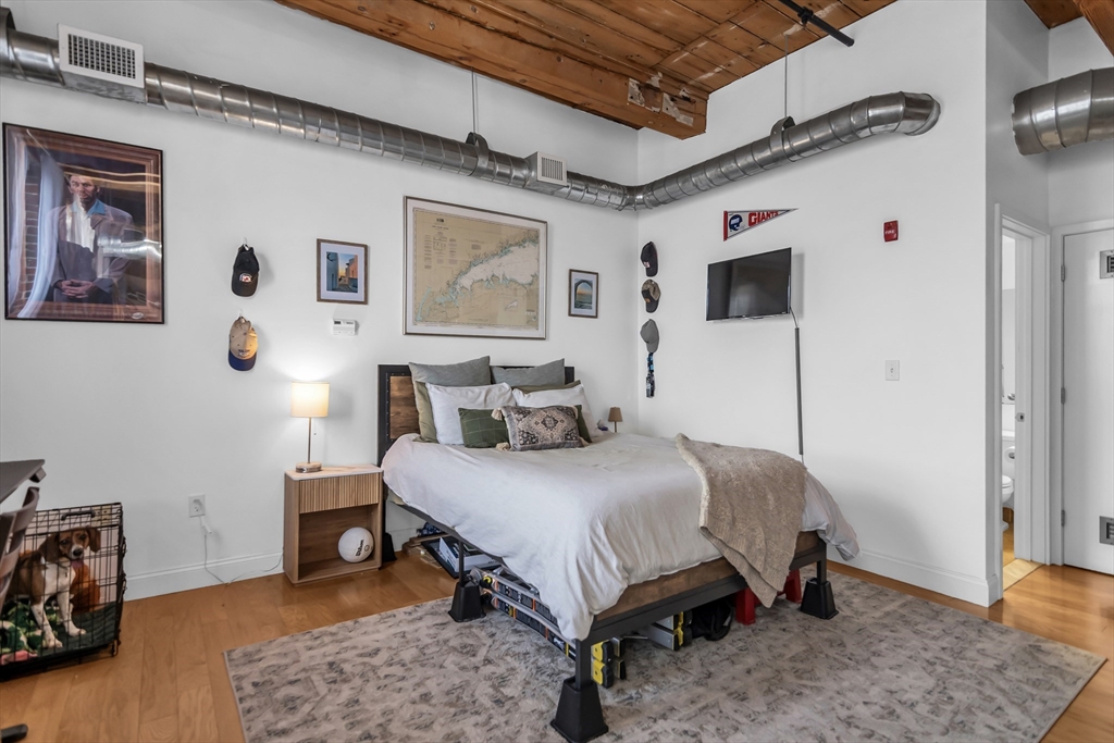 130 John Street, Unit 216 Lowell, MA 01852 - Photo 7 of 17 a bedroom with a bed a table and chair