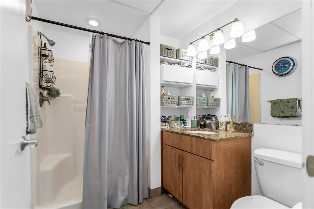 130 John Street, Unit 216 Lowell, MA 01852 - Photo 8 of 17 a bathroom with a sink a toilet a mirror a vanity and shower